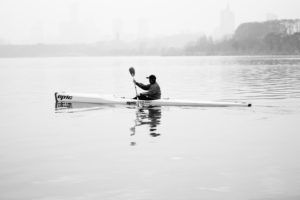 A man is paddling with his kayak through a lake in Nanjing, China A man is paddling with his kayak through a lake in Nanjing, China